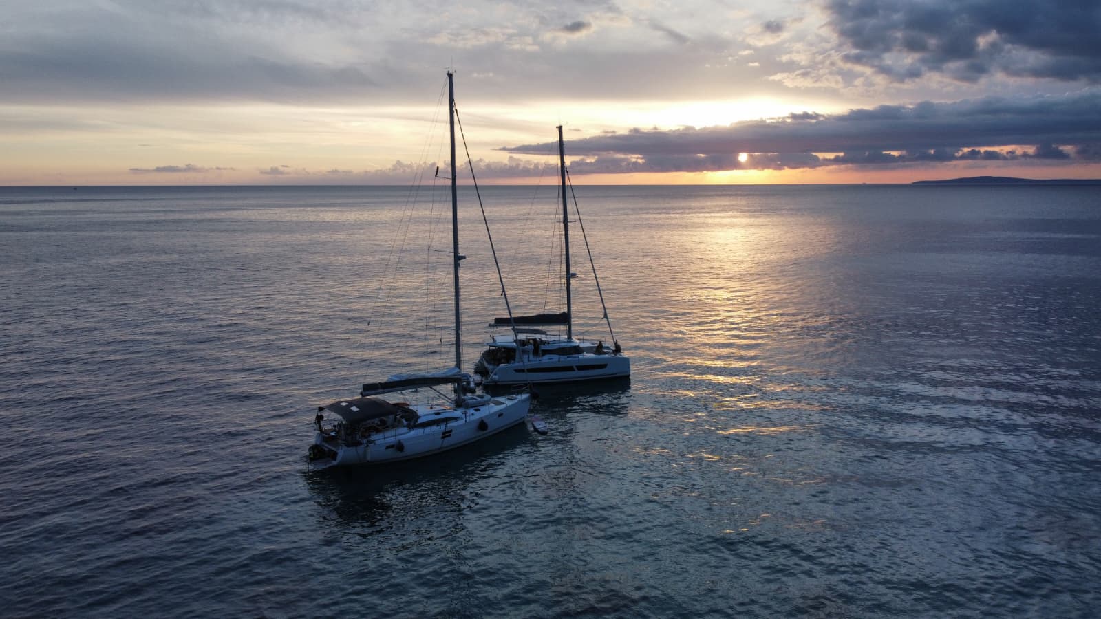 Two yachts at anchor under a sunset sky